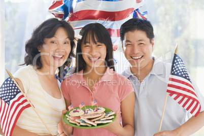 Family outdoors on fourth of July with flags and cookies smiling