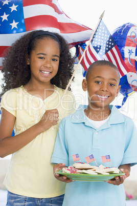 Brother and sister on fourth of July with flag and cookies smili