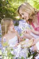Mother and daughter on Easter looking for eggs outdoors smiling