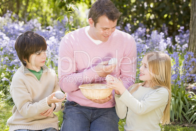 Father and two young children on Easter looking for eggs outdoor