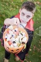 Young boy outdoors wearing vampire costume on Halloween holding