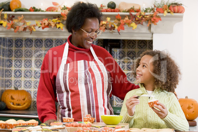 Grandmother and granddaughter making Halloween treats and smilin
