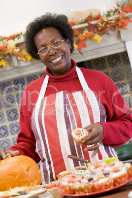 Woman in kitchen making Halloween treats and smiling