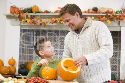 Father and son carving jack o lanterns on Halloween and smiling