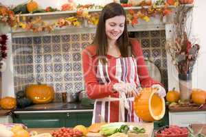 Woman carving jack o lantern on Halloween and smiling