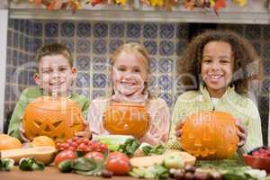 Three young friends on Halloween with jack o lanterns and food s