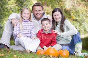 Family sitting on grass with pumpkins smiling