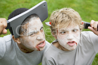 Two young boys with scary Halloween make up and plastic knives t