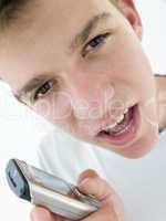 Teenage boy using cellular phone and looking mad