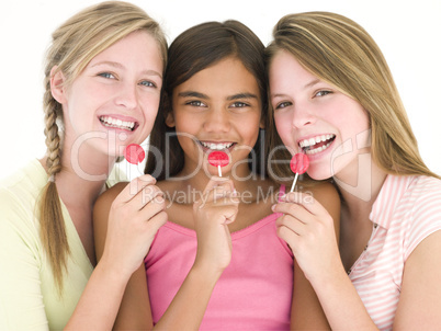 Three girl friends with suckers smiling