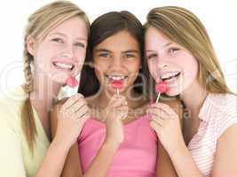 Three girl friends with suckers smiling