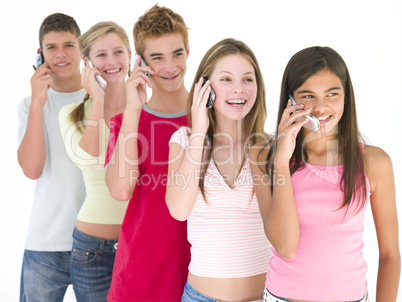 Row of five friends on cellular phones smiling