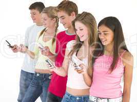 Row of five friends using cellular phones smiling