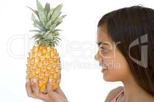 Young girl holding pineapple and smiling