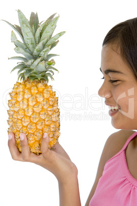 Young girl holding pineapple and smiling