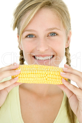 Teenage girl holding corn on cob and smiling