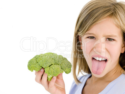 Young girl holding broccoli and sticking tongue out