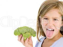 Young girl holding broccoli and sticking tongue out