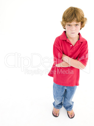 Young boy with arms crossed scowling