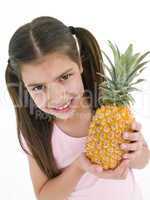 Young girl holding pineapple and smiling