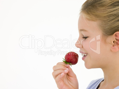 Young girl eating strawberry smiling