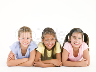 Row of three friends lying down smiling