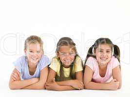 Row of three friends lying down smiling