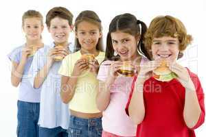 Row of five young friends eating hamburgers