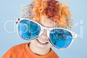 Young boy wearing clown wig and sunglasses smiling