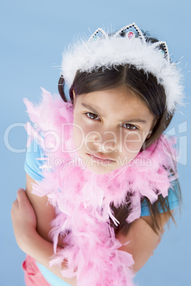 Young girl wearing crown and feather boa frowning