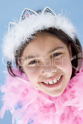 Young girl wearing crown and feather boa smiling