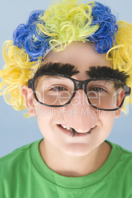 Young boy wearing clown wig and fake nose smiling