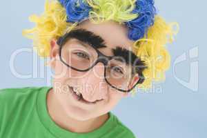 Young boy wearing clown wig and fake nose smiling