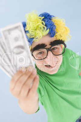 Young boy wearing clown wig and fake nose holding money