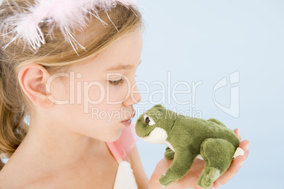 Young girl in princess costume kissing plush frog