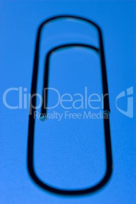 Close Up Of A Blue Paperclip, Against A Blue Background