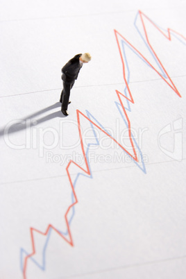 Figurine Of A Businessman Standing On A Line Graph