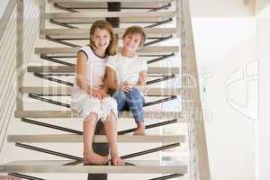 Two Young Girls Sitting On A Staircase At Home