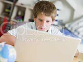 Young Boy Using Laptop In His Bedroom