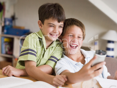 Two Young Boys Distracted From Their Homework, Playing With A Ce