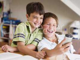 Two Young Boys Distracted From Their Homework, Playing With A Ce