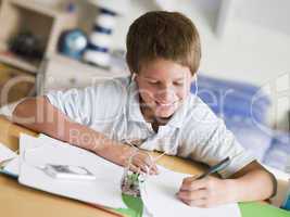 Young Boy Doing His Homework While Listening To Music On His MP3