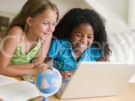 Two Young Girls Doing Their Homework On A Laptop