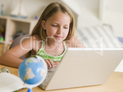 Young Girl Doing Homework On A Laptop