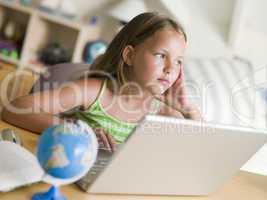 Young Girl Doing Homework On A Laptop