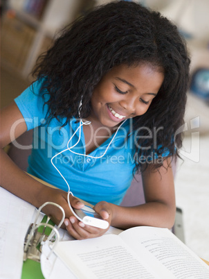 Young Girl Distracted From Her Homework, Playing With An MP3 Pla