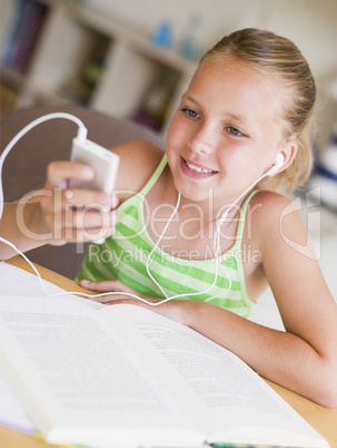 Young Girl Distracted From Her Homework, Playing With An MP3 Pla