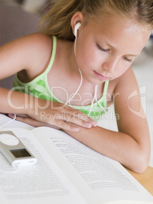 Young Girl Reading A Book While Listening To An MP3 Player