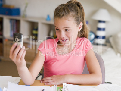 Young Girl Distracted From Her Homework, Playing With A Cellphon