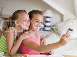 Young Girls Distracted From Their Homework, Playing With A Cellp